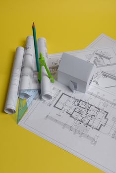 White family paper house, house projects plan and blueprints in the background. Minimalistic and simple concept, style. Horizontal orientation. View from above.