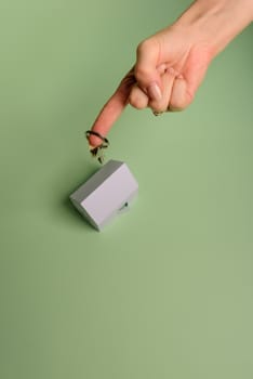 White family paper house. House keys in hand on mint background paper. Minimalistic and simple concept, style. Copy space. Vertical orientation. Family moving or removal concept.