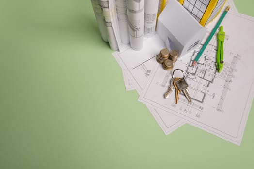 White family paper house. House keys in hand on mint background paper. Minimalistic and simple concept, style. Copy space. Vertical orientation. Family moving or removal concept.