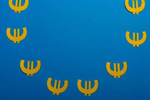 Paper yellow symbols of euro currency on blue background. View from above with copy space