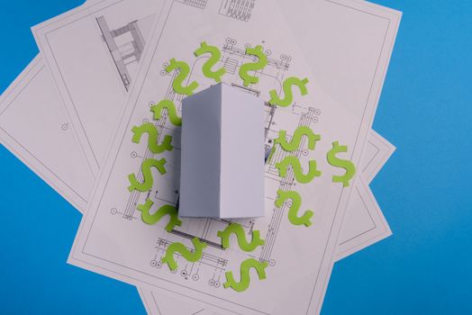 Paper skyscrapers , us dollar money, house projects plan and blueprints on blue background paper. Minimalistic and simple concept, style. Horizontal orientation. View from above. Copy space.