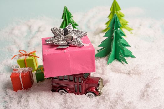 a toy car carries presents under the Christmas tree at snow. view from above. copy space