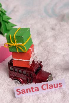 a toy car carries presents under the Christmas tree at snow. view from above. copy space