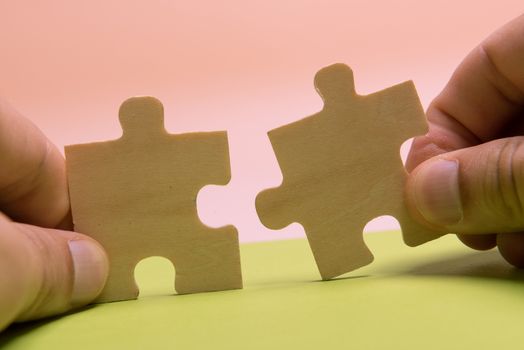 Man hand assembling puzzles on lime background.