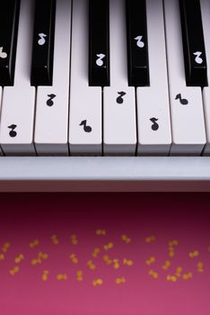 white toy piano with paper notes. music piano concept. view from above. White, black and yellow music notes.