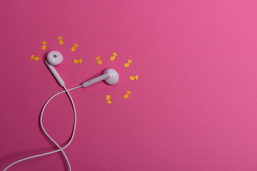 white earphones and white paper notes on orange background. view from above