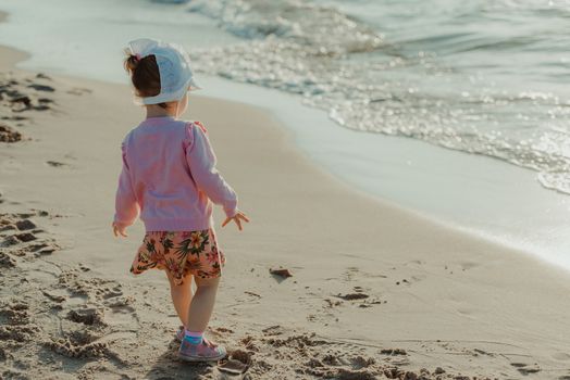 Adorable toddler girl on a sunny sand beach. Authentic childhood