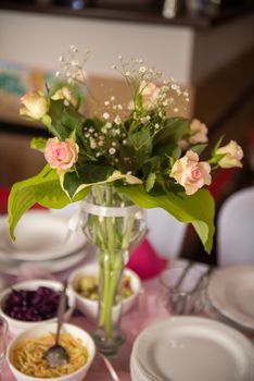 Pastel roses in turquoise vase and decorative heart on white wooden background. Selective focus.
