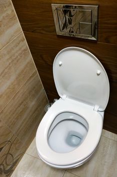 Flush toilet with white tiles in background, front view