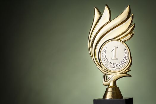 Gold winners trophy for a championship event with flames surrounding a medallion over a green background with copy space