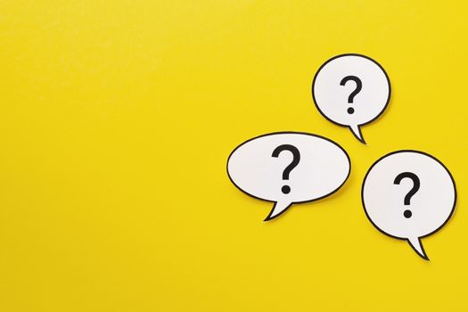 Three different shaped speech bubbles with question marks inside over a bright yellow background