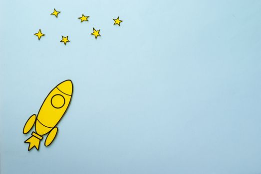 Yellow rocket with booster flames flying to the stars over a blue background with copy space in a conceptual image