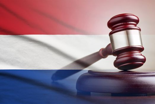 Legal gavel on its plinth over a flag of the Netherlands in a conceptual composite image