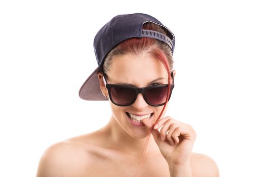 Beautiful stylish girl with backwards snapback cap and sunglasses, looking at the camera and biting her nail seductively, isolated on white background.