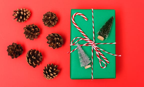 New Year, Christmas Xmas holiday composition, Top view gift green box, clews of rope and green fir tree branch on red background with copy space