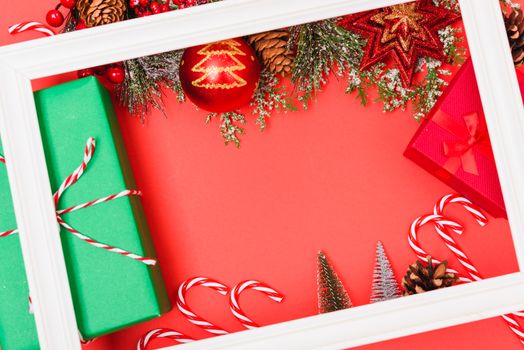 Christmas composition decorations, with white Photo frame square and fir tree branches on red background. Merry Christmas concept. Copy space for text