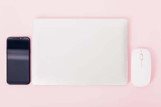 Top view of modern technology smart phone mobile and computer laptop close cover on pink background with copy space