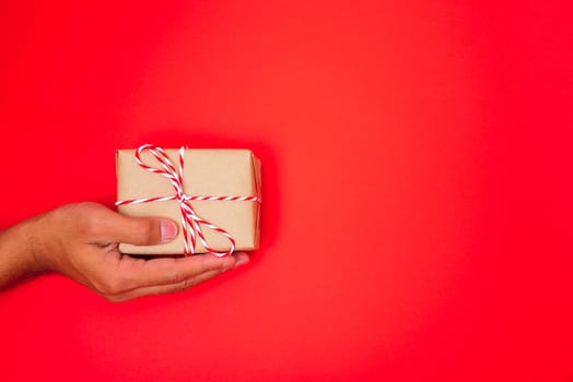 Happy New Year and Christmas 2020 or valentine day, top view hands with Brown gift box on red background with copy space for your text