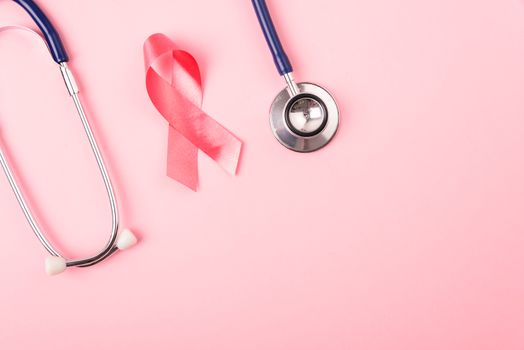 Breast Cancer Awareness Month Health concept, top view flat lay pink ribbon and stethoscope on pink background with copy space for your text