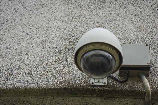 Large white CCTV on light beige stone wall of public buildings