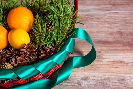 Christmas or new year  fruit basket top view. Oranges and lemon lie in a basket with a Christmas tree and Christmas cones. New year flat lay with copy spase