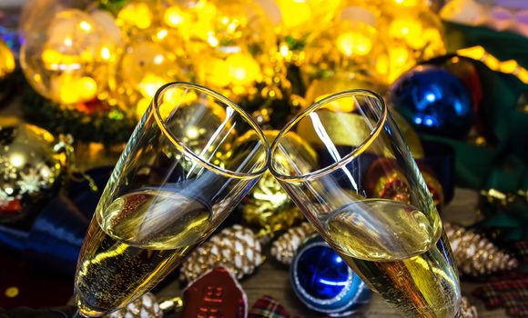 Glasses of champagne on the Christmas table with Christmas toys and garlands. New year and Christmas with glasses of champagne, holiday 2020.