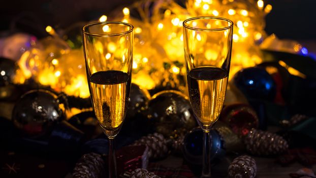 Glasses of champagne on the Christmas table with Christmas toys and garlands. New year and Christmas with glasses of champagne, holiday 2020.