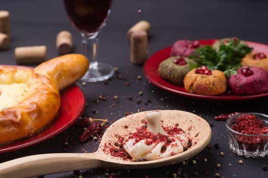 Georgian food on black table. khinkali, phali,  khachapuri with tomatos, adjika and a glass of wine.