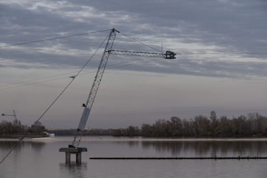 Seagull sitting on a rope above the river. Many clouds with gray tone. It can start raining.