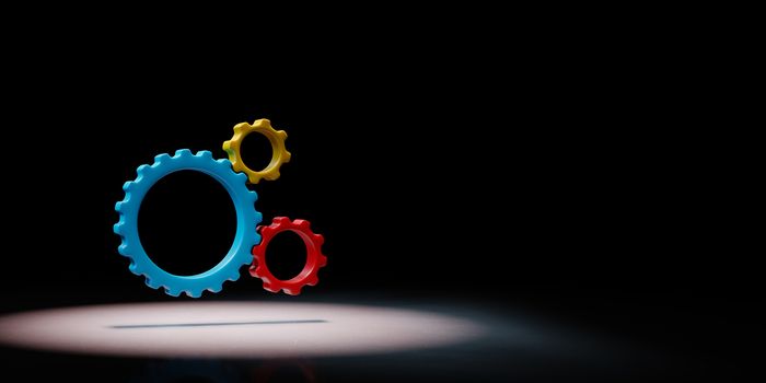 Three Plastic Colorful Gears Engaged Spotlighted on Black Background with Copy Space 3D Illustration