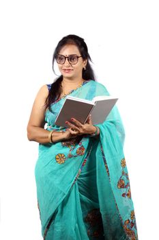 A middle aged Indian teacher in tuquoise saree, on white studio background.