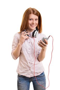 Portrait of a beautiful young girl with headphones around her neck, holding a phone and smiling, isolated on white background. Girl looking to play her favorite music.