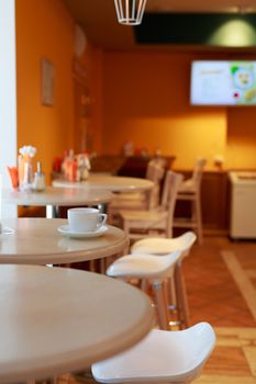 coffee Cup is on the table in a cafe with a blurry background , white tea Cup, Breakfast, cafe background orange