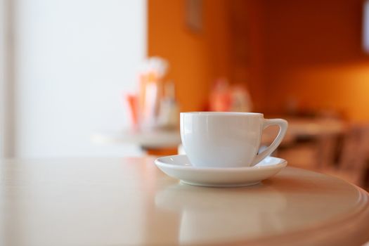 coffee Cup is on the table in a cafe with a blurry background , white tea Cup, Breakfast, cafe background orange