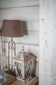 wooden lantern painted white old paint peeling vintage, standing on the table, next to a brown old lamp with a brown shade