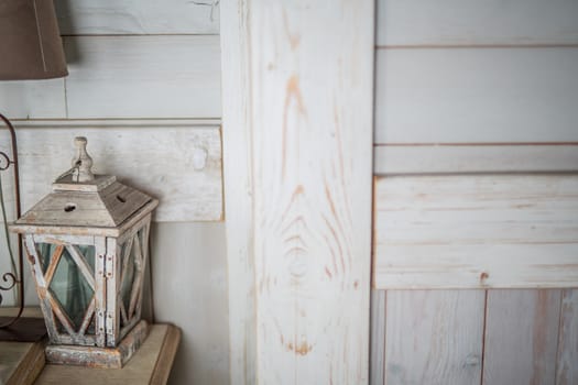 wooden lantern painted white old paint peeling vintage, standing on the table, next to a brown old lamp with a brown shade