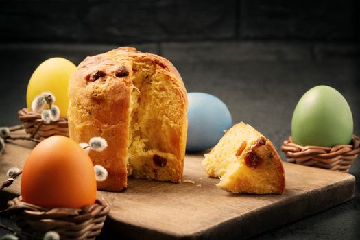 Easter cake on a cutting board and colored eggs - traditional easter breakfast.