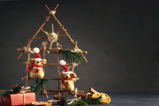 Two little toy Christmas mice, gift and decorations on a black table. Christmas composition with the symbol of 2020 according to the Chinese horoscope.