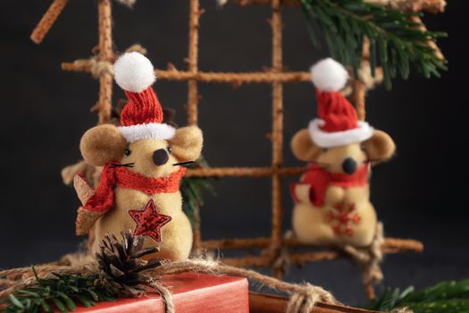 Two little toy Christmas mice, gift and decorations on a black table. Christmas composition with the symbol of 2020 according to the Chinese horoscope, close up