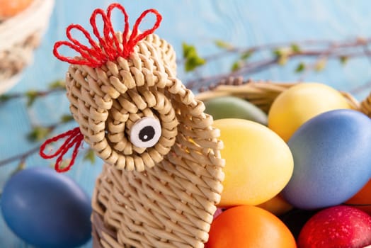 Wicker basket in the form of a chicken with colorful Easter eggs - easter composition.