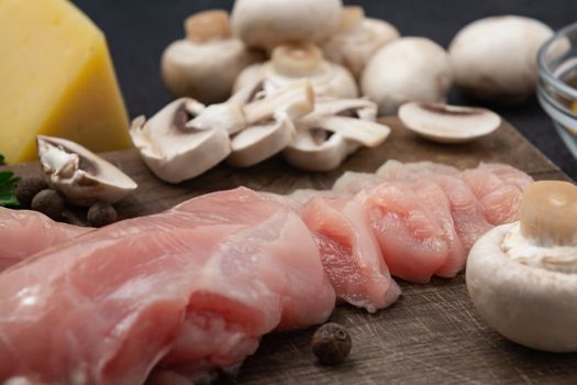 Slicing chicken breast fillet for cooking with champignons and cheese.