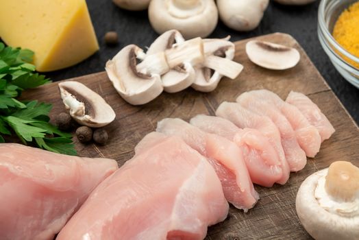 Slicing chicken breast fillet for cooking with champignons and cheese.