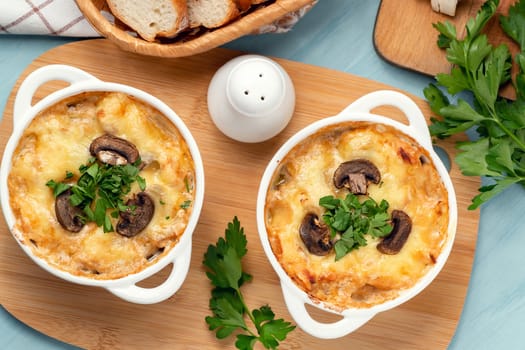 Casserole with chicken, mushrooms and cheese, known in Russia as julienne in white bowls with herbs, top view, flat lay.