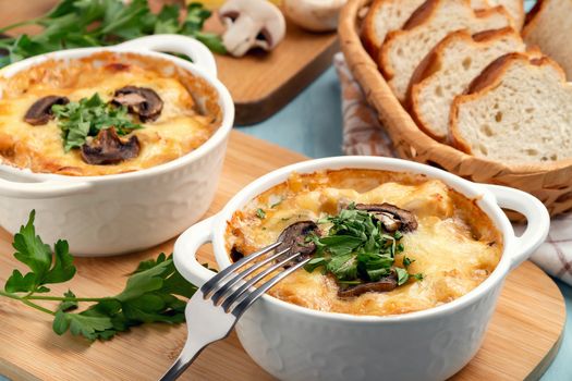 Casserole with chicken, mushrooms and cheese, known in Russia as julienne in white bowls with herbs.