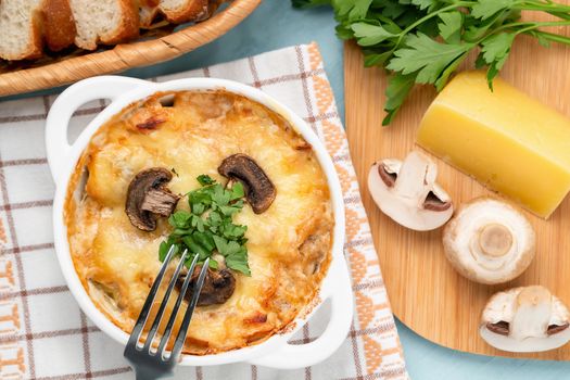 Casserole with chicken, mushrooms and cheese, known in Russia as julienne in white bowl with herbs, top view, flat lay.