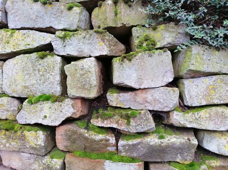 Old stone wall with moss and holes texture background.