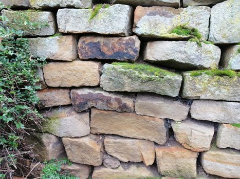 Old stone wall with moss and holes texture background.