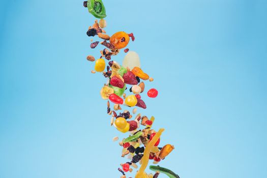 Dried and candied fruits and nuts flying on blue background. Stock photo of healty and nutrient food. Conceptual photo of vegan and vegetarian healty food.