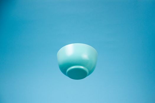 A blue ceramic mattle deep bowl for breakfast flying on blue background. Ideal photo for levitation of food and fruits or nuts.