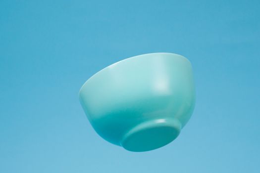 A blue ceramic mattle deep bowl for breakfast flying on blue background. Ideal photo for levitation of food and fruits or nuts.